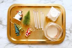 a tray with candles, ornaments and other items on it sitting on a marble surface