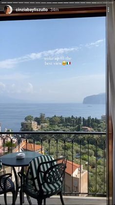 balcony with table and chairs looking out to the sea from outside apartment building in italy