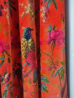 an orange curtain with colorful birds and flowers on it