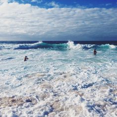 two people in the ocean with surfboards