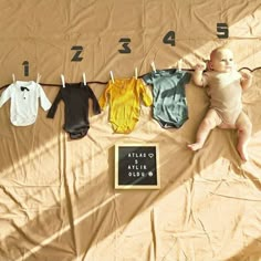 a baby laying on top of a bed next to clothes and a sign that says it's 4 o'clock