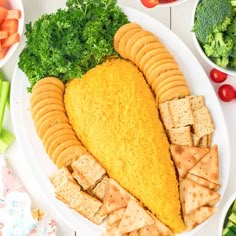 a platter filled with crackers, cheese and veggies next to bowls of vegetables