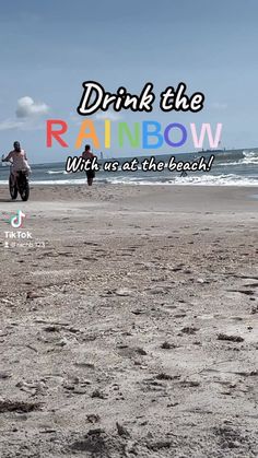 a man riding a motorcycle on top of a sandy beach next to the ocean with words drink the rainbow