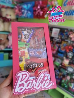 a person holding up a pink box with candy in it and the words barbie on it