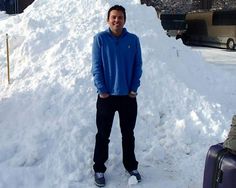 a man standing in the snow next to a pile of snow