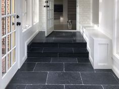 a black and white tiled hallway leading to an open door with a dog on the other side