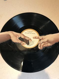 two hands reaching out to each other on top of a record