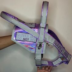 a person is holding a purple and silver reflective dog harness that says service dogs don't fit