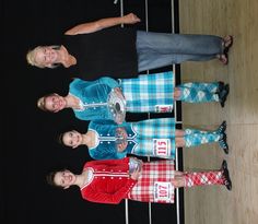 three people standing next to each other in front of a wooden floor and black background