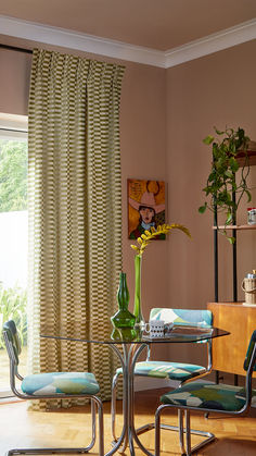 a dining room table with chairs and a vase filled with flowers