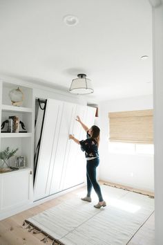 a woman standing on top of a rug in front of a white wall and door