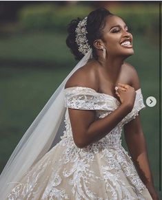 a woman in a wedding dress is smiling and looking off to the side with her hand on her shoulder