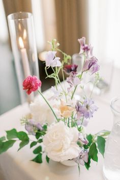 a vase filled with flowers sitting on top of a table next to a lit candle