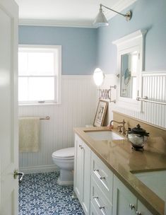 a bathroom with blue and white tile flooring next to a sink, toilet and window