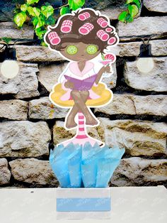 a paper cut out of a girl standing on top of a blue umbrella in front of a stone wall