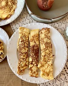 three plates with french toast on them sitting on a table next to an apple and other desserts