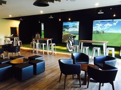 a room with chairs, tables and golf simulators