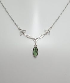 This is a new handmade necklace. It is made with antiqued silver plated Celtic knots, accented with a high quality LIGHT PERIDOT GREEN glass jewel that sparkles like crystal. Decorated portion is 2 1/2" wide and 1 1/4" tall in the center. Necklace is adjustable 15-18" with a lobster clasp and chain extender. If you would like a different length, please send us a message.Matching earrings and headpiece are listed in our store in a variety of stone colors. If you don't see items with a color you w Peridot Necklace Silver, Handmade Silver Peridot Necklaces, Silver Pendant Necklace With Peridot, Celtic Emerald Necklace, Green Peridot Pendant Necklace, Celtic Goddess, Choker Pendant, Peridot Green, Celtic Knots