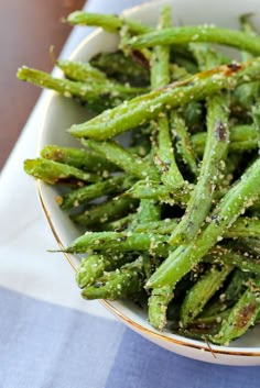 a white bowl filled with green beans covered in seasoning