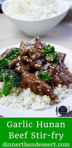 a white plate topped with beef and broccoli covered in gravy next to rice