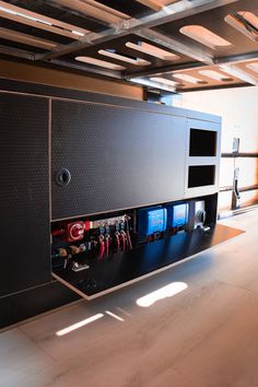 a large black cabinet with many tools in it's compartments and some lights on the ceiling