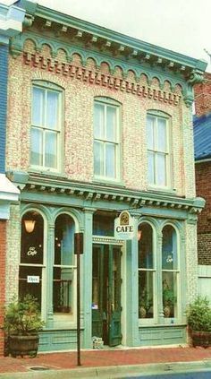 an old brick building on the corner of a street with potted plants in front