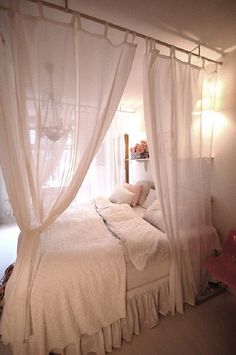 a white bed sitting under a window next to a red chair