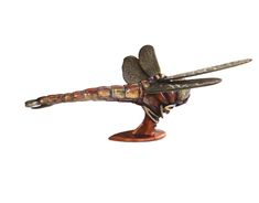 a dragonfly figurine sitting on top of a wooden stand with its wings spread