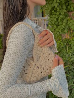 a woman holding a crocheted purse in her hands