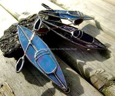 three stained glass canoes sitting on top of a wooden table