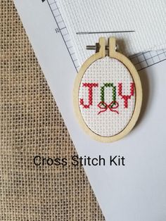 a cross stitch kit with a small hoop hanging from it's side on a piece of fabric