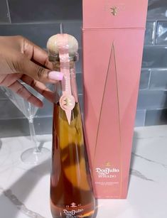 a person holding a wine bottle in front of a pink box