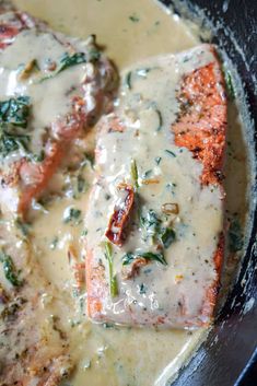 two pieces of meat covered in gravy and spinach on top of a skillet