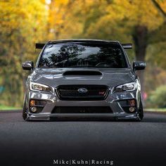 a subarun parked on the side of a tree lined road