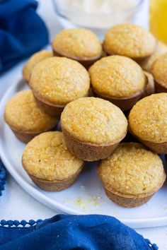 a white plate topped with muffins next to a glass of orange juice and blue napkin