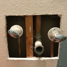 two metal knobs on the side of an electrical outlet in a wall with peeling paint