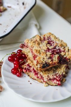 two pieces of cake on a white plate with cherries next to the rest of the dessert