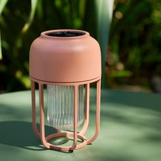 a pink light that is sitting on top of a table with plants in the background