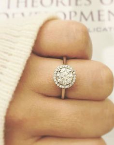 a close up of a person's hand holding a diamond ring