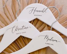 three wooden clothes hangers with names on them sitting next to some fanned straws