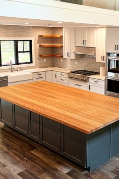 Kitchen island with character cherry countertop, dark blue cabinets with surrounding white cabinets, hardwood flooring in an open kitchen space. Cherry Butcher Block Countertops, Cherry Kitchen Island, Block Countertops, Island Countertop, Cherry Kitchen, Cherry Stain, Countertop Design