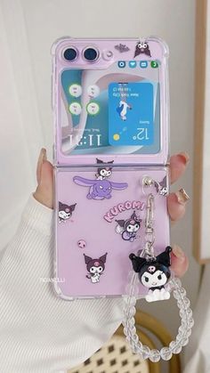 a person holding up a cell phone case with charms attached to the back of it