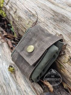 a wallet sitting on top of a piece of wood with a button in the pocket