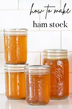 three jars filled with honey sitting on top of a counter next to a white brick wall