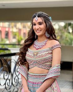 a beautiful young woman in a dress and jewelry posing for the camera with her hands on her hips