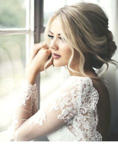 a woman is looking out the window with her hand on her chin and wearing a white lace dress