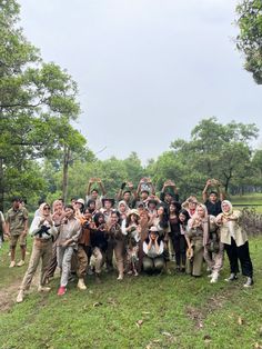 a group of people standing on top of a lush green field next to each other