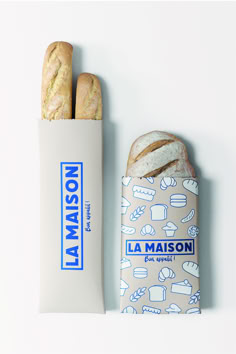 two loaves of bread sitting next to each other on a white surface with blue writing that says la maison