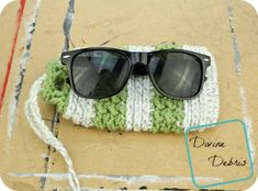 a pair of black sunglasses sitting on top of a green and white knitted bag