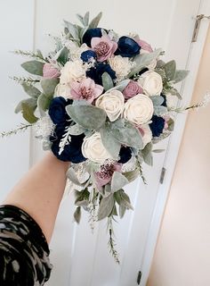 a bridal bouquet being held by someone's hand in front of a door